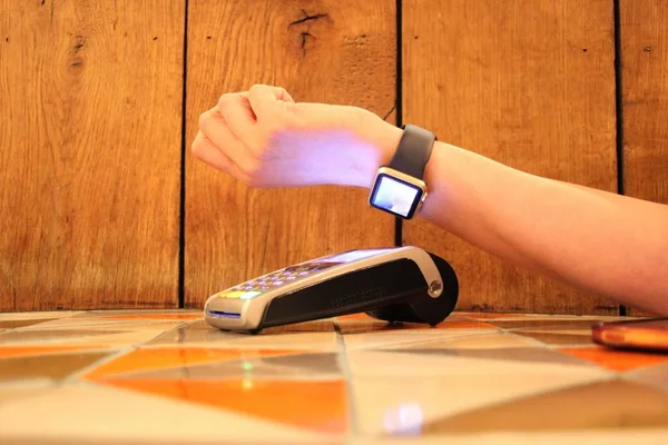 Contactless payment watch pdq with hand holding credit card to pay — Stock Photo, Image