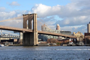 New York, ABD - 20 / 12 / 2019: New York 'taki Brooklyn köprüsü, Hudson Nehri' nin karşısındaki Manhattan gökdelenleri.