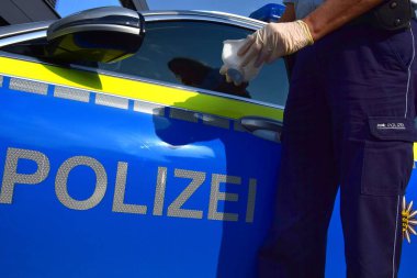 Kategori FFP2 'nin solunum maskesi takan, lastik eldiven takan ve polis arabasının yanında duran bir Alman polis memuru. Polis için 