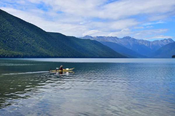 Sarı bir kanoyla Rotoroa Gölü 'nde kürek çeken bir adam. Arka planda dağlar. Nelson Lakes Ulusal Parkı, Tasman, Yeni Zelanda, Güney Adası.