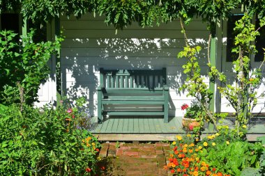 Verandada yeşil bir bank, bitkilerle çevrili..