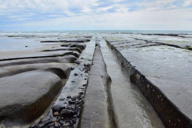 Yeni Zelanda 'nın güney adasının kuzeybatı kıyısındaki kayalar ve kayalıklar dalgalar tarafından sürüklenir..