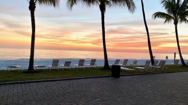 Fort Myers Plajı, FL - Bir sıra boş sandalye güneş batarken Meksika Körfezi 'ne bakıyor