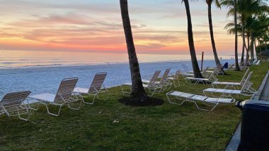 Fort Myers Sahili, FL - Güneş batarken plaj sandalyeleri boşalır ve huzurlu bir ortam oluşur.