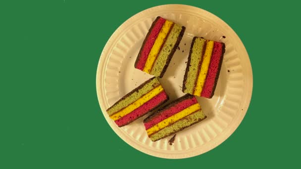 Кусочки Радужного Торта Тарелке Разным Цветовым Фоном — стоковое видео