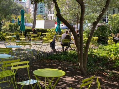 New York 'taki Union Square Park' ta metalik masa ve sandalyelerde dinlenen insanlar