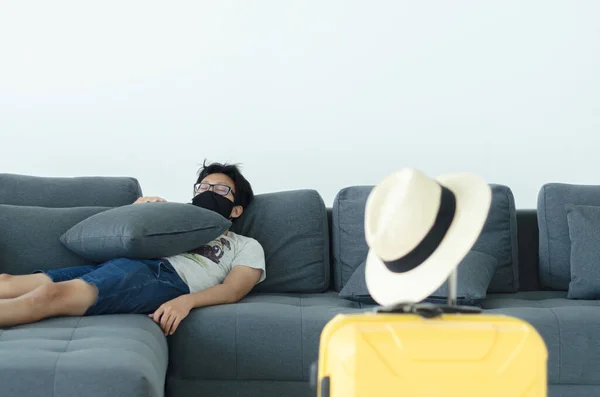 Asian Men Wearing Glasses Wearing a black mask Sleeping on the gray sofa in his room.A sick man is sleeping.On the gray sofa someone was resting.