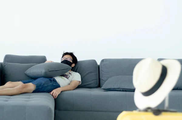 Asian Men Wearing Glasses Wearing a black mask Sleeping on the gray sofa in his room.A sick man is sleeping.On the gray sofa someone was resting.