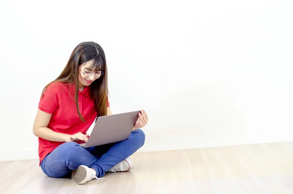 一个漂亮的亚洲女人 穿着红色衬衫 戴着眼镜 拿着笔记本电脑笑着 免版税图库图片