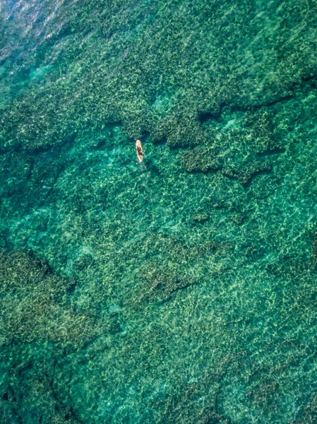 夏威夷珊瑚礁上方滑板上的冲浪运动员的自上而下的照片 — 图库照片