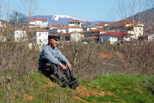 March 25th 2011, Korestia, Greece - Old man sitting on the ground and staring, near Korestia village, Kastoria, Greece