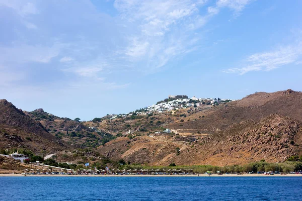 Pláž na ostrově Patmos s chora na vrcholu hory — Stock fotografie