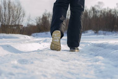 Karlı bir kış gününde parkta tek başına yürüyen bir adam. Yürüme konsepti. Bir yayanın arka görünümü.