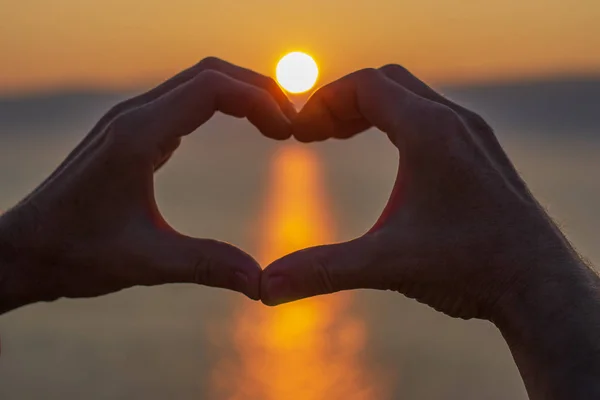 Mens hands in the shape of a heart on a background of the sky at sunset. Love concept. Heart-shape hand gesture — 스톡 사진