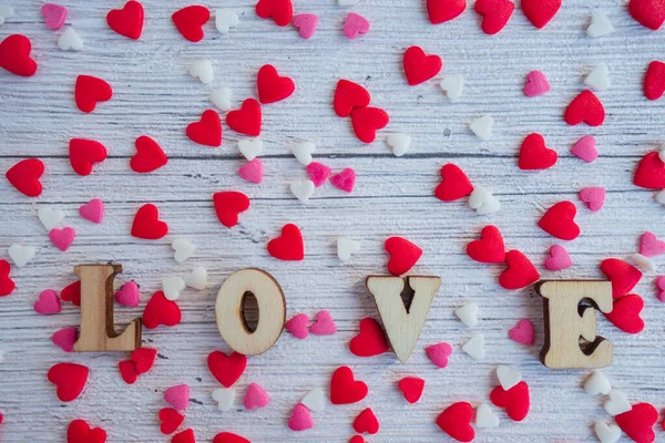 La palabra amor en letras de madera sobre un fondo de rojo, rosa, corazones blancos. Feliz Día de San Valentín, Día de las Madres, 8 de marzo, Día Mundial de la Mujer concepto de tarjeta de vacaciones . — Foto de Stock