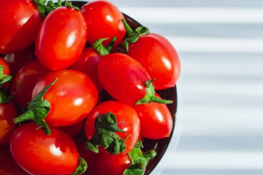 Siyah bardakta yeşil saplı küçük vişneli domatesler. Yakın plan. Metin için boşluk