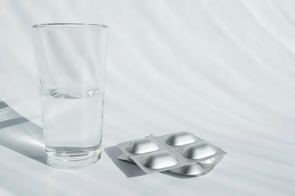 Een Glas Water Een Blister Met Pillen Een Lichte Achtergrond — Stockfoto