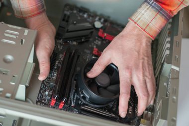 Sistem birimine yeni bir anakart yükleniyor. Bilgisayar onarımı ve güncellemesi. Bilgisayarı tamir eden bir ustanın ellerine yakın çekim