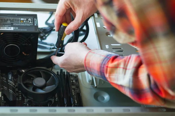 Installing a new motherboard in the system unit. Computer repair and upgrade. Close-up of the hands of a master repairing a computer