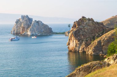 Olkhon Adası ve Burhan Burnu 'nun kayalık kıyıları batan güneşin altında bir yaz akşamıdır. Baykal Gölü 'nün mavi sularında eğlence tekneleri