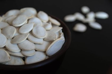 Siyah bir fonda kahverengi bir fincanda kabak çekirdeği. Vejetaryen ve vejetaryen yemekleri. Faydalı bir atıştırma. Sağlıklı yiyecekler. Metin için boşluk.