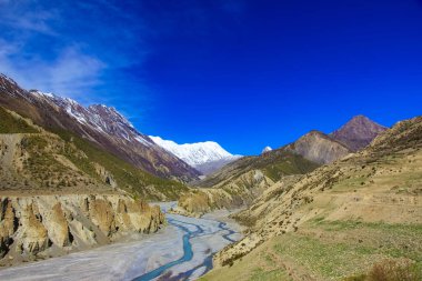 Nepal dağlarında bir nehir. Uzak kar zirveleri ve mavi gökyüzü