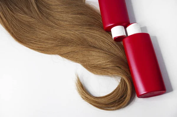 Mooie lange haar en shampoo flessen op een witte achtergrond — Stockfoto