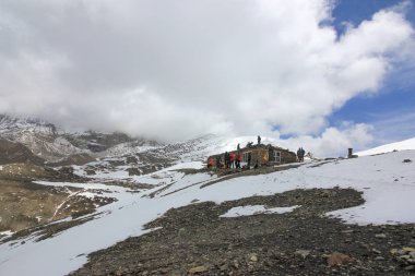 Mavi gökyüzüne karşı beyaz bulutlu karlı dağlar. Dağ