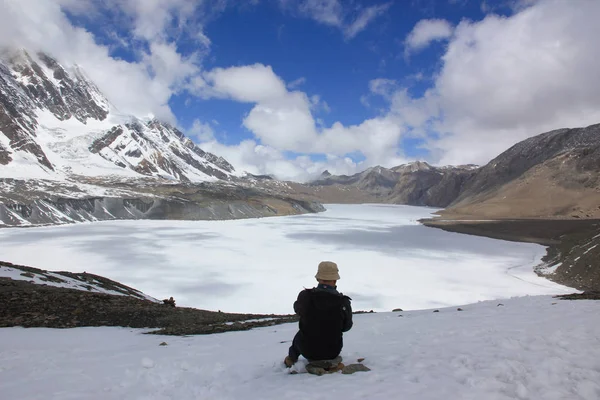 Ένας άνθρωπος κάθεται με την πλάτη του στην κάμερα δίπλα σε μια παγωμένη λίμνη στο m — Φωτογραφία Αρχείου