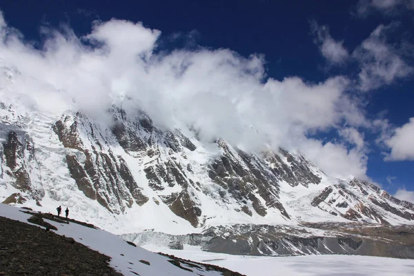 Χιονισμένα βουνά ενάντια στον γαλάζιο ουρανό με άσπρα σύννεφα. Όρος — Φωτογραφία Αρχείου