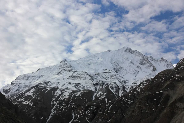 Besneeuwde bergen tegen de blauwe lucht met witte wolken. Berg — Stockfoto