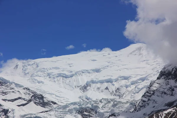Schneebedeckte Berge gegen den blauen Himmel mit weißen Wolken. Berg — Stockfoto