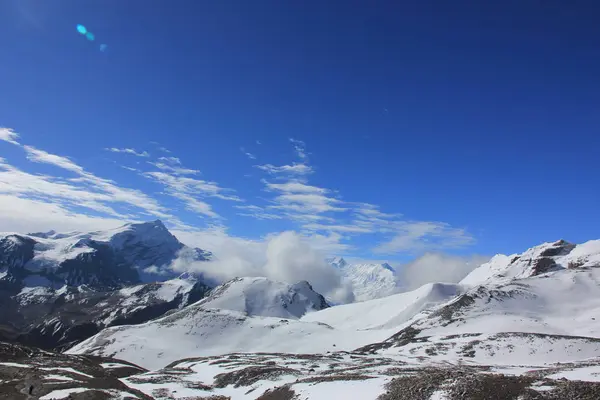 Montañas nevadas contra el cielo azul con nubes blancas. Montaña —  Fotos de Stock