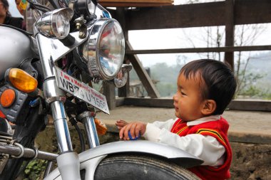 Hintli çocuk dışarıda, büyük bir motosikletin yanında. Nisan 2015, Hindistan
