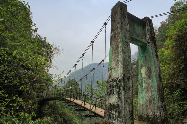 Large suspension bridge among green trees. India