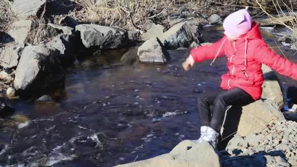 Κορίτσι Κάθεται Ένα Βράχο Και Πέταξε Μια Πέτρα Στο Ποτάμι — Αρχείο Βίντεο