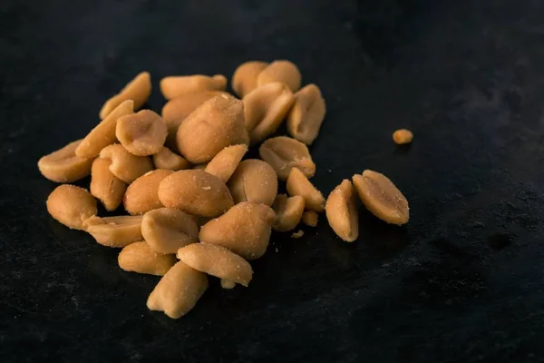 Heap of salted peanuts on dark tray — Stock Photo, Image