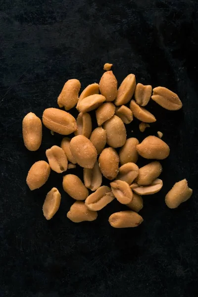 Top view on heap of salted peanuts on dark tray — Stock Photo, Image