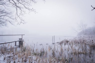 Gölet ve ahşap yaya köprüsü ile karlı kış manzara