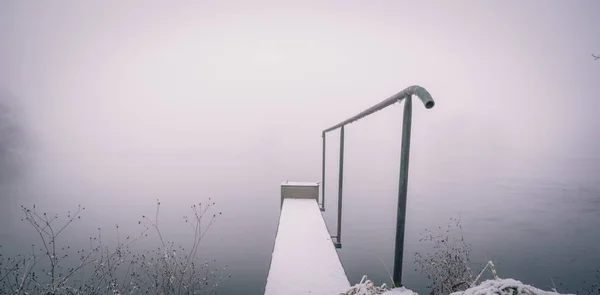Zasněžené lávka s kovovým zábradlím kolem rybníka — Stock fotografie