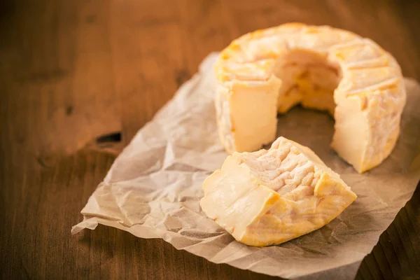 Porción cortada de queso camembert dorado entero sobre mesa de madera —  Fotos de Stock
