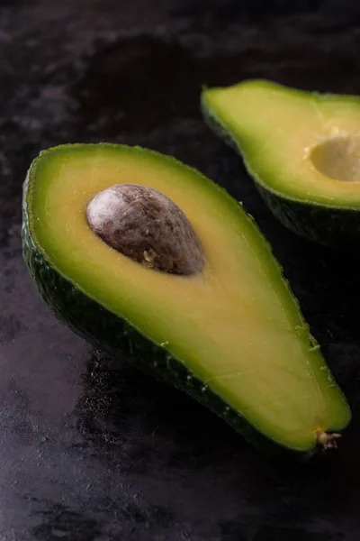 Einzelne Avocado halbiert auf abgetragenem dunklen Tablett — Stockfoto