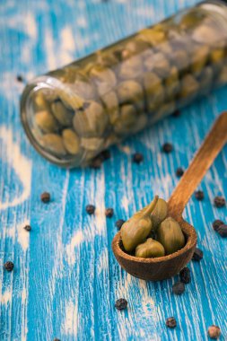 Tahta kaşık ile cam kavanoz içinde birkaç Kapari