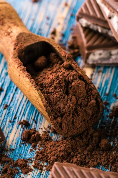 Cacao en cuchara y chocolate con relleno cremoso sobre mesa azul —  Fotos de Stock
