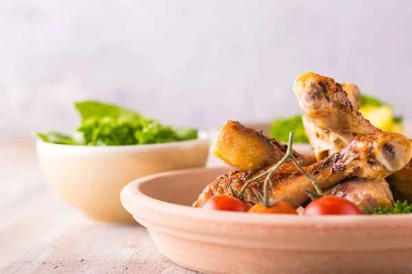 Porción de unas patas de pollo en plato frente a papas y ensalada verde — Foto de Stock