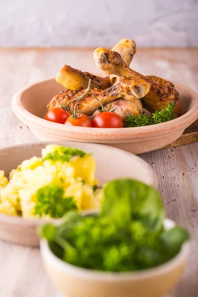 Porción de unas patas de pollo en el plato detrás de papas y ensalada — Foto de Stock