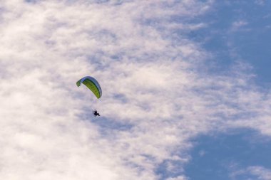 Yeşil kanatlı ve arkada motorlu yamaç paraşütü