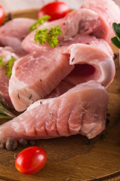 Несколько филе свинины на доске с травами и помидорами — стоковое фото