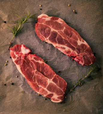 Çiğ domuz biftek biberiye ve biber tohumları üzerinde kağıt levha ile iki dilim