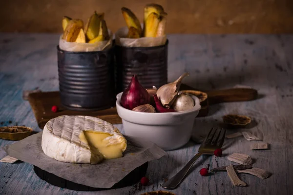 Soğan ve patates kızartması ile ahşap tahta üzerinde sıcak erimiş camembert peyniri